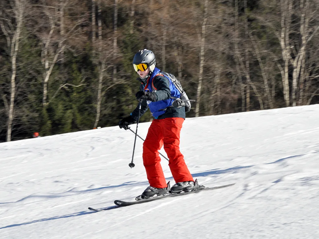 Skifahrer in roter Hose zieht einen Schwung.